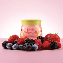 Pink jar with yellow lid labeled "Wildberry Fields Aloe & Shea Cream" surrounded by strawberries, raspberries, blackberries,