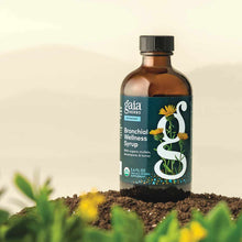 Gaia Herbs Bronchial Wellness Syrup in 5.4 fl oz amber bottle with dark teal label and black cap on soil with plants.