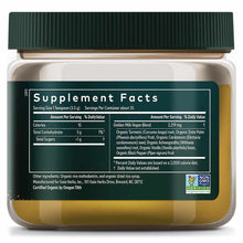 Glass jar with green cap containing golden-yellow powder supplement with dark teal label displaying nutrition facts.