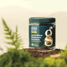 Gaia Herbs Lion's Mane Mushroom Gummies bottle with dark teal label, 60 count, displayed on soil with green plants.