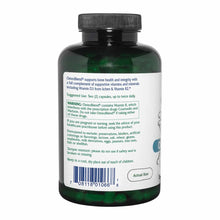 A dark green supplement bottle with a black cap, turned to show a white label with usage directions, warnings, and a barcode.