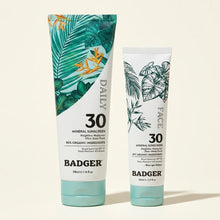 Two Badger SPF 30 mineral sunscreen tubes with tropical leaf designs: larger daily body sunscreen (118ml) and smaller face su