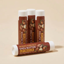 Four Desert Essence Shea Butter Lip Rescue tubes with white caps and brown labels featuring shea nuts graphics.