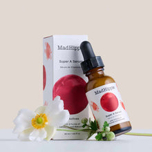 Mad Hippie Super A Serum bottle with dropper next to white packaging box, displayed with white flower and green leaves.