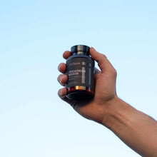 Dark blue bottle labeled Testosterone Booster by Olympian Labs held in hand against light blue background.