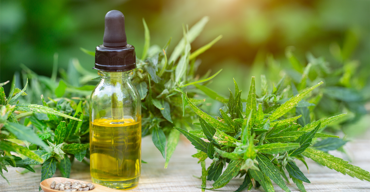 A glass CBD container with marijuana plants in the background