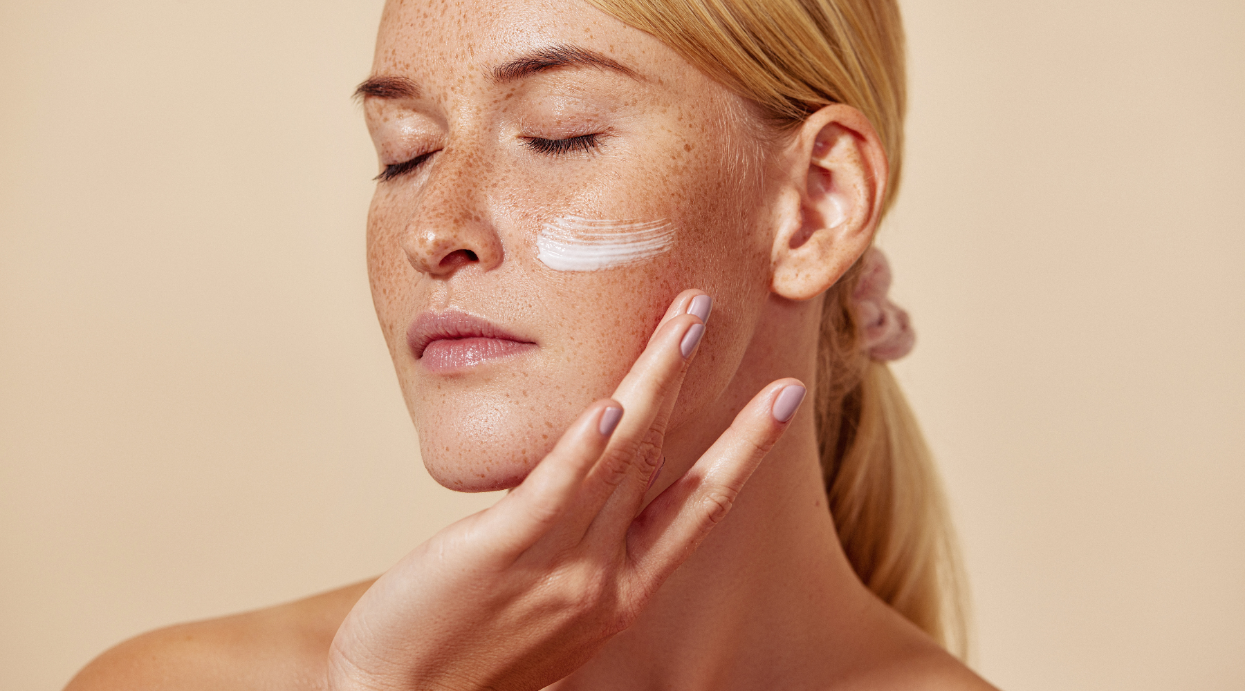 Young women brushing moisturizer on her cheek