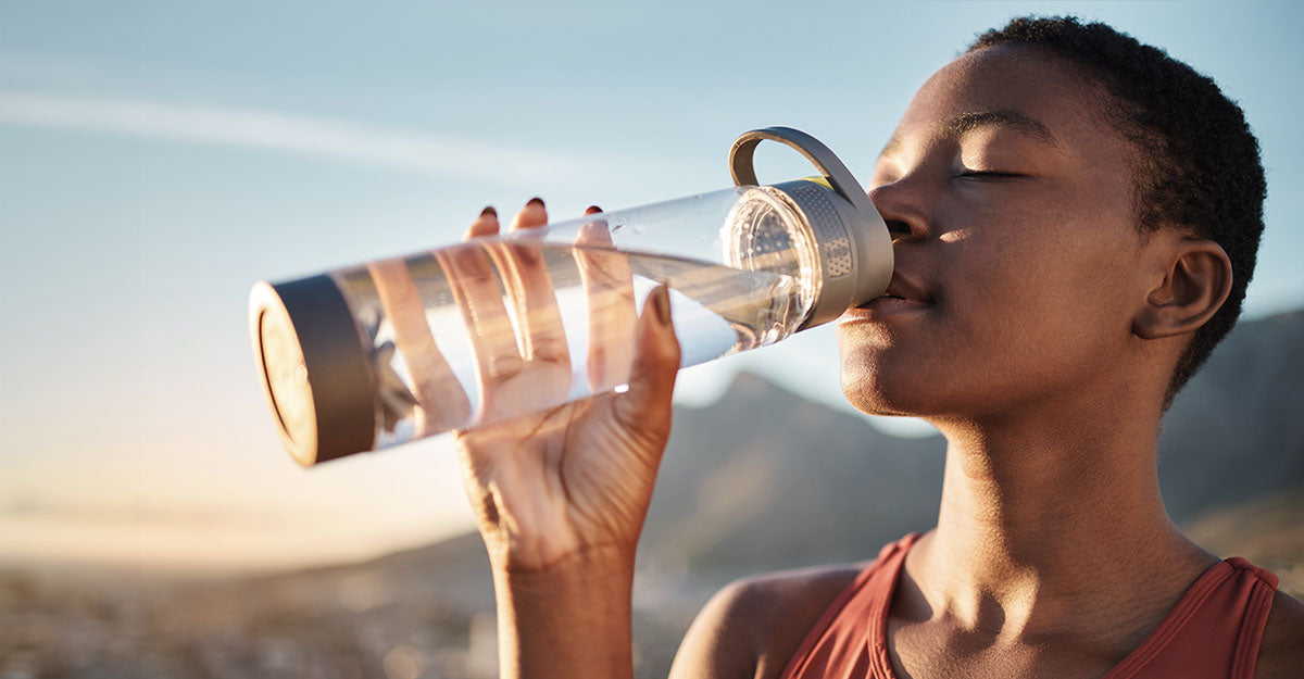 Women outdoors drinking electrolytes out of a water bottle