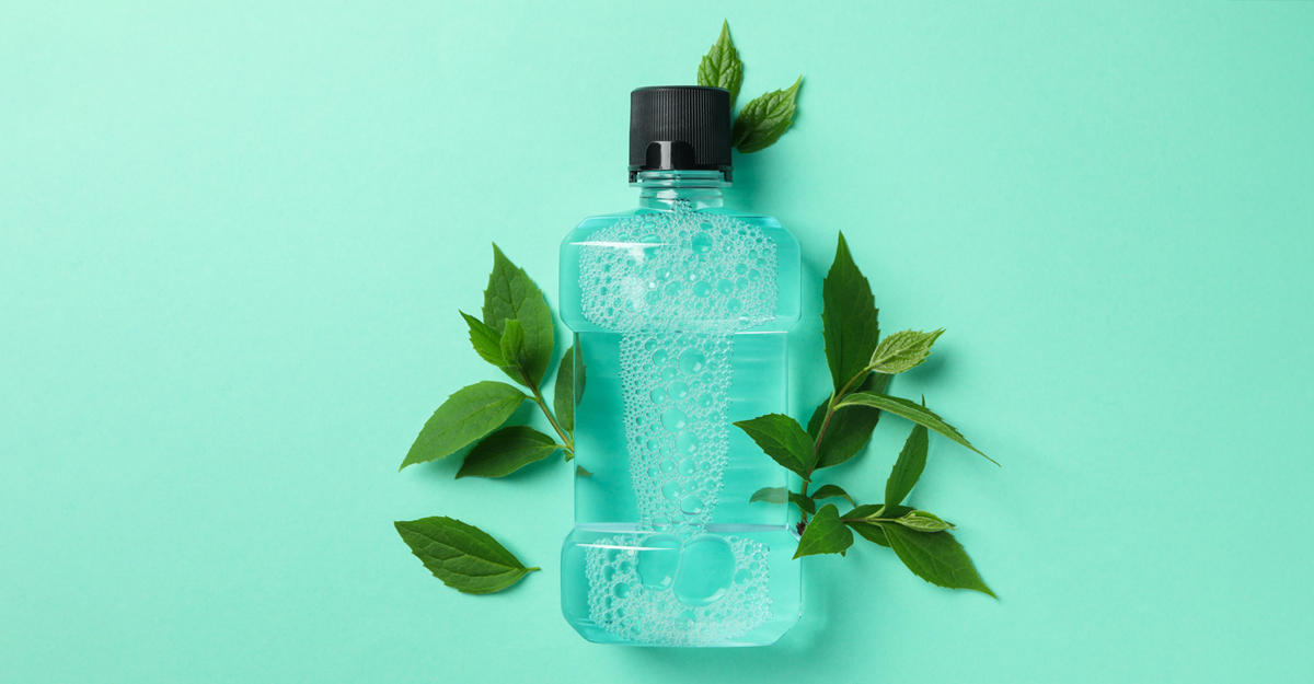 A mouthwash bottle with mint leaves surrounding them