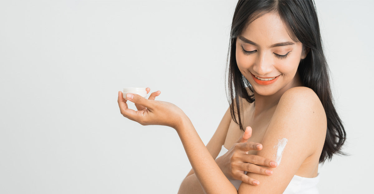 A young women putting lotion on her arm