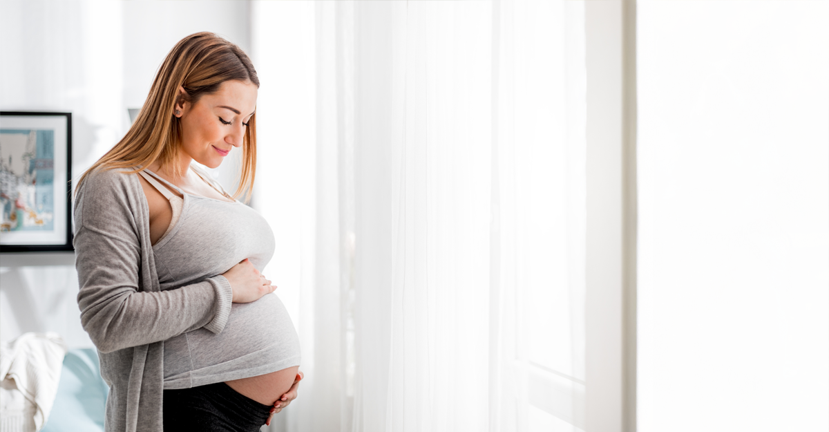 A pregnant women looking down at her stomach
