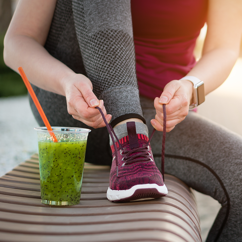 Person tying shoe with nutritional drink