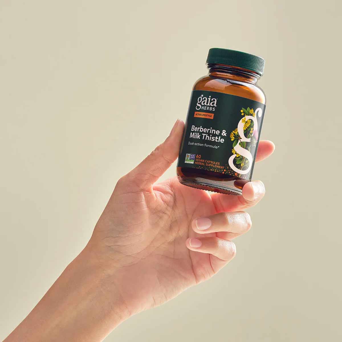 Gaia Herbs Berberine & Milk Thistle supplement bottle held in hand against neutral background.