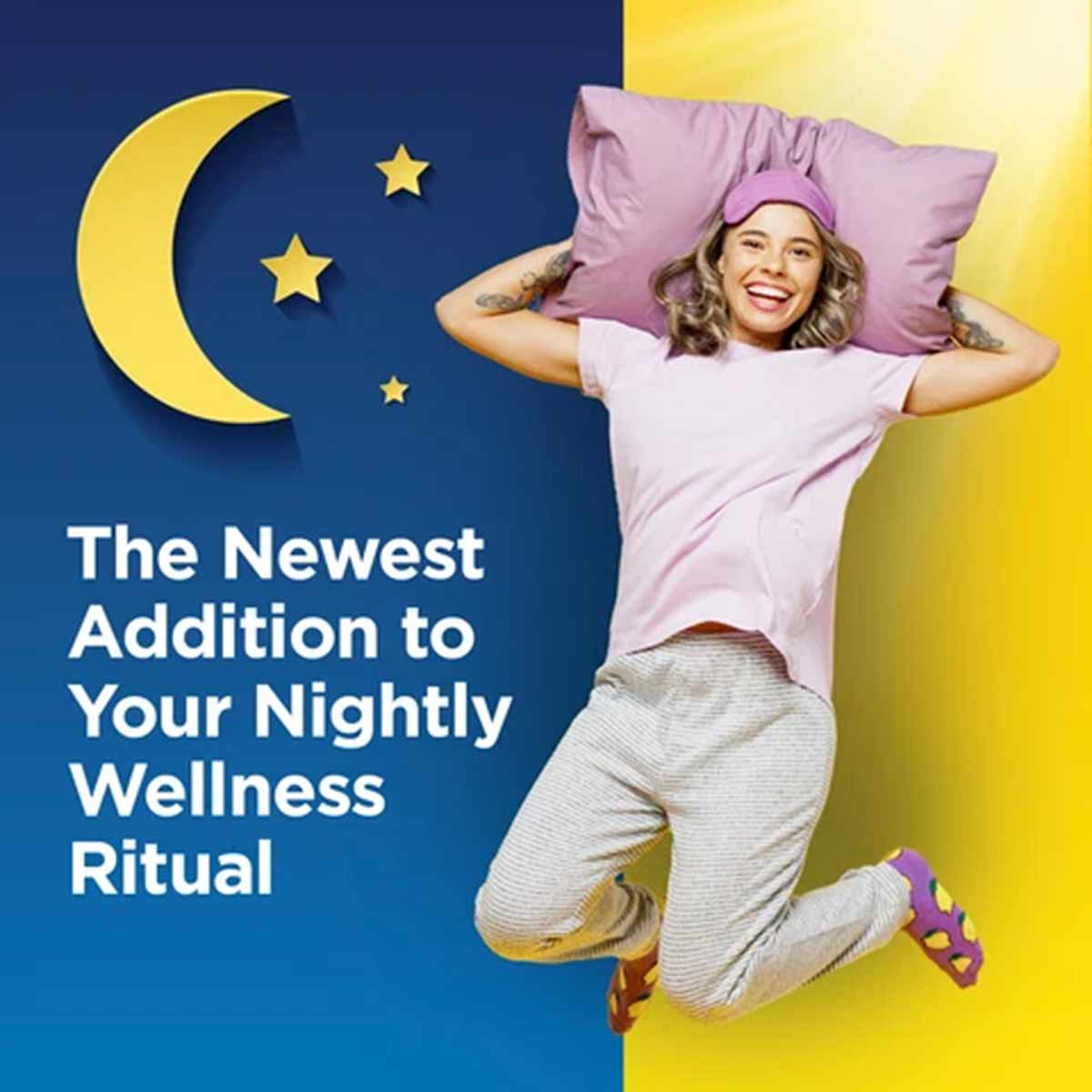Woman in white shirt and beige pants holding pink pillow against blue and yellow background with moon and stars.