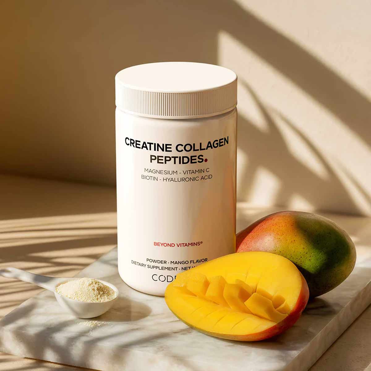 White cylindrical container of Codeage Creatine Collagen Peptides powder with mango flavor, displayed with fresh mango slices