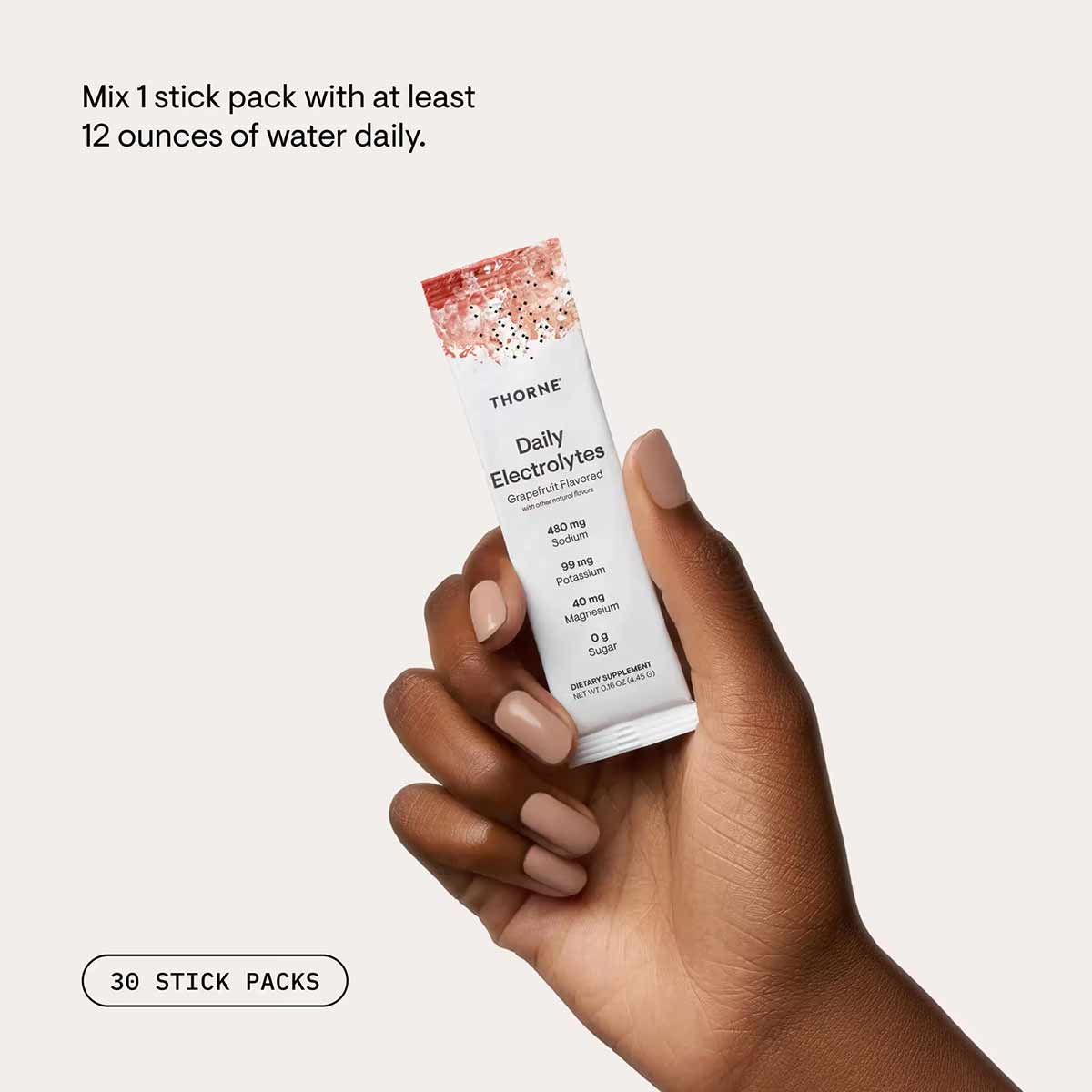 Thorne Daily Electrolytes stick pack with grapefruit flavor held in hand, showing ingredient amounts including sodium and pot