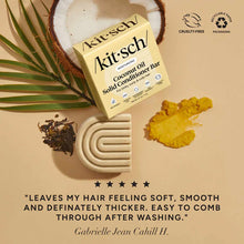 Pale yellow rectangular Kitsch coconut oil conditioner bar surrounded by coconut halves, ginger root, dried tea leaves, and g
