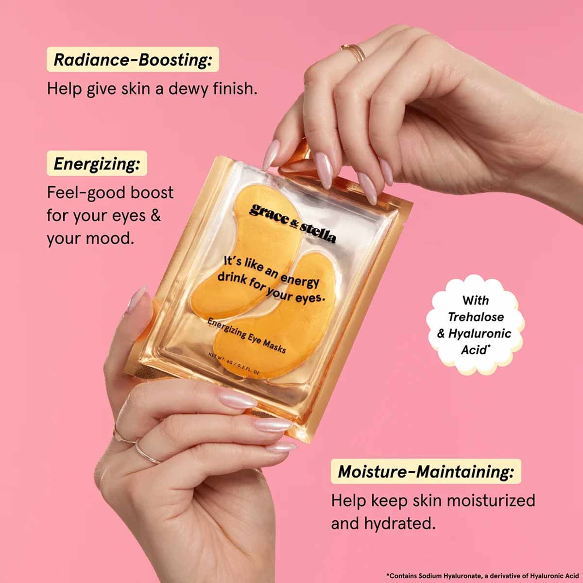 Person's hands holding gold-packaged under eye masks against pink background with product benefit callouts.