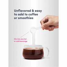 Hand holding white scoop pouring collagen peptides into mug of dark coffee.