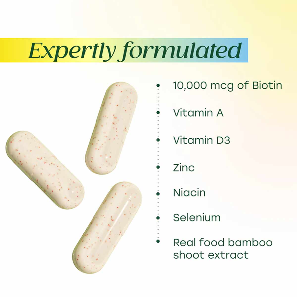 Three cream-colored capsules with red specks next to ingredient list including biotin, vitamins, minerals, and bamboo extract