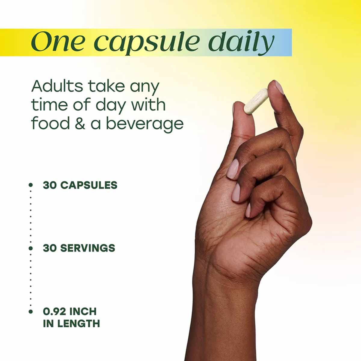 Hand holding a single white capsule with product details: 30 capsules, 30 servings, 0.92 inch length, one daily with food.