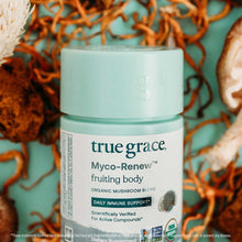 Light blue jar of True Grace Myco-Renew fruiting body organic mushroom blend supplement with label visible, surrounded by dri