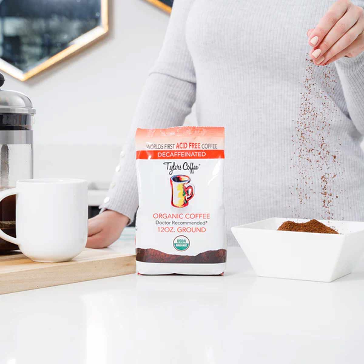 Tyler's organic decaf ground coffee 12 oz bag with person pouring grounds into white bowl.