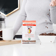 Tylers Coffee decaffeinated organic whole bean coffee 12 oz bag displayed next to white mug and bowl of beans.