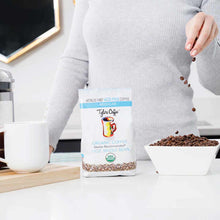 Tylers Coffee organic whole bean coffee bag with beans pouring into white bowl on desk.