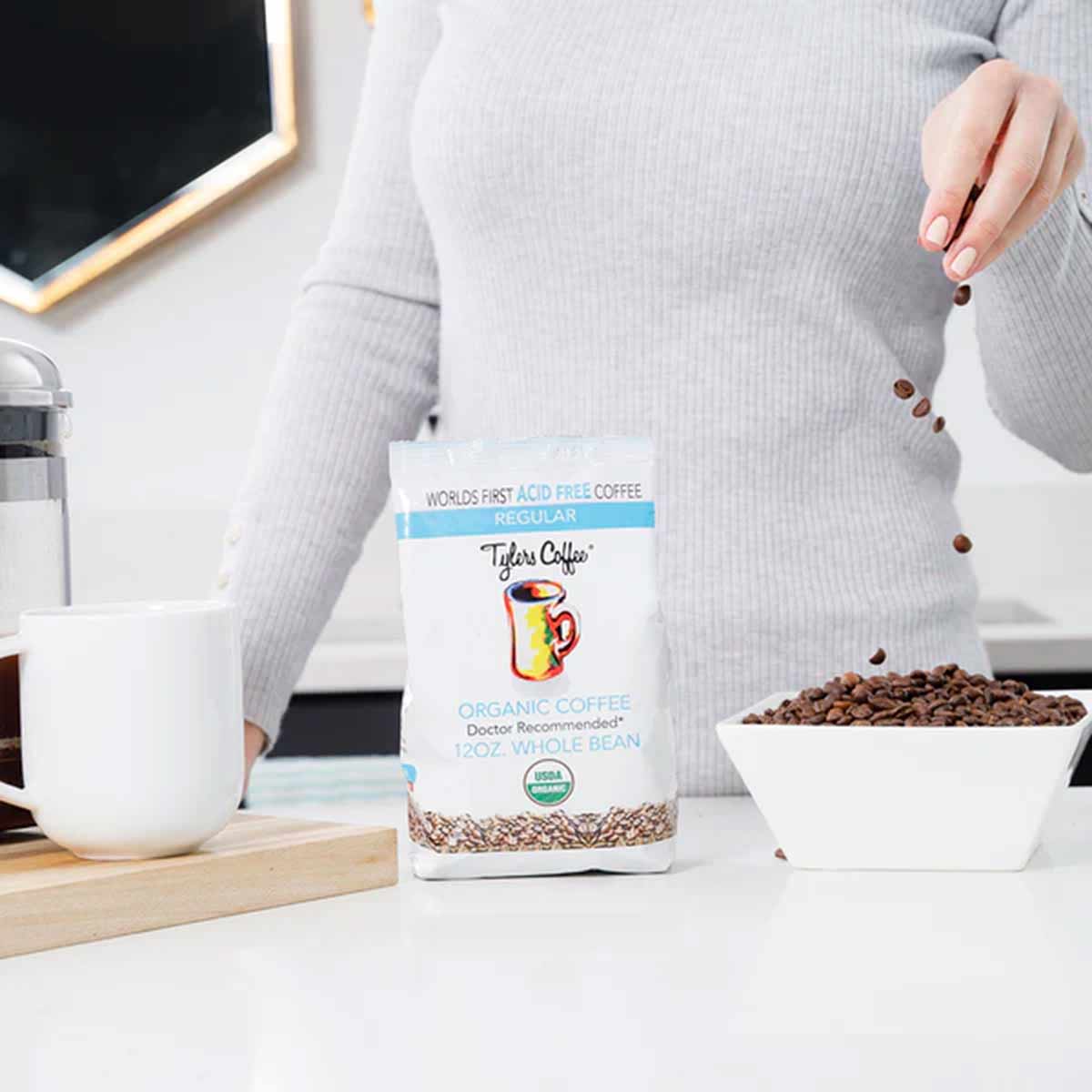 Tylers Coffee organic whole bean coffee bag with beans pouring into white bowl on desk.