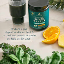 Teal container of Ancient Nutrition Organic SuperGreens + Bloat Relief powder with glass of green beverage, orange slices, an