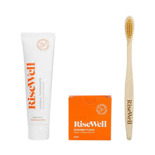 RiseWell toothcare bundle containing white tube of mineral toothpaste, orange box of scrubby floss, and wooden toothbrush wit
