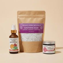 Brown glass bottle with spray top labeled "Look Beautiful Botanical Serum," kraft pouch of organic herbal bath salts, and gla