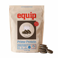 A tan Equip Prime Protein pouch in cookies and cream flavor stands beside a small stack of chocolate sandwich cookies.