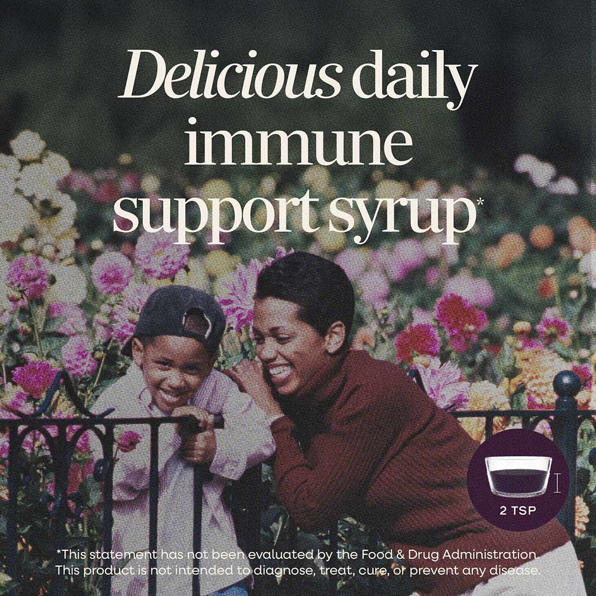 Dark purple elderberry syrup in a bottle with a 2 TSP measuring cup indicator and text describing immune support.
