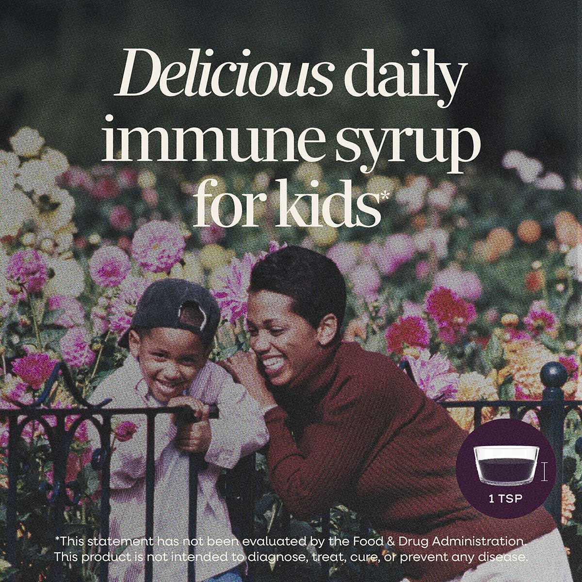 Dark purple liquid syrup in a measuring spoon, displayed over a background of two children in a flower garden.