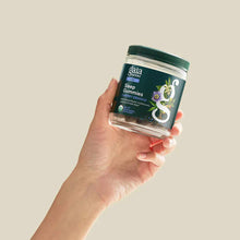 Hand holding dark green glass jar of Gaia Herbs Sleep Gummies in cherry orange flavor with white label and green cap.