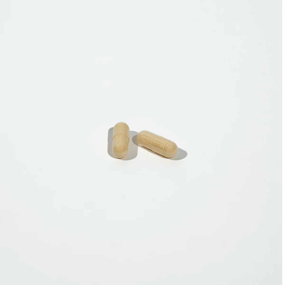 Two tan capsules on a white background.