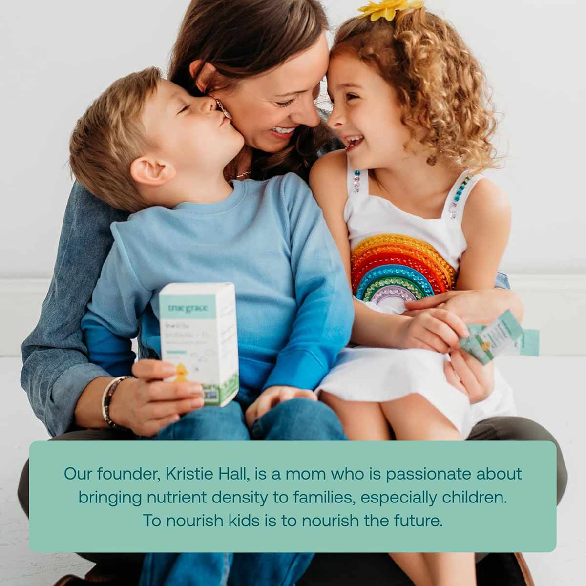 Woman holding probiotic supplement box with two children, one holding individual stick packs.