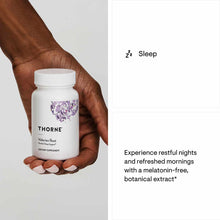 White bottle of Thorne Research Valerian Root dietary supplement held in a hand against a gray background.