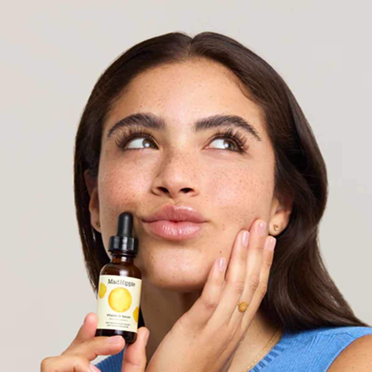 Mad Hippie Vitamin C Serum bottle with dropper held by person applying product to face.