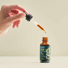 Hand holding dropper above amber bottle of Gaia Herbs Wormwood Black Walnut Supreme liquid extract.